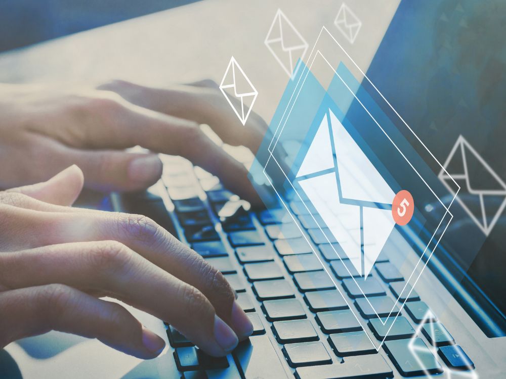 Hands typing on a laptop with illustrated email envelopes